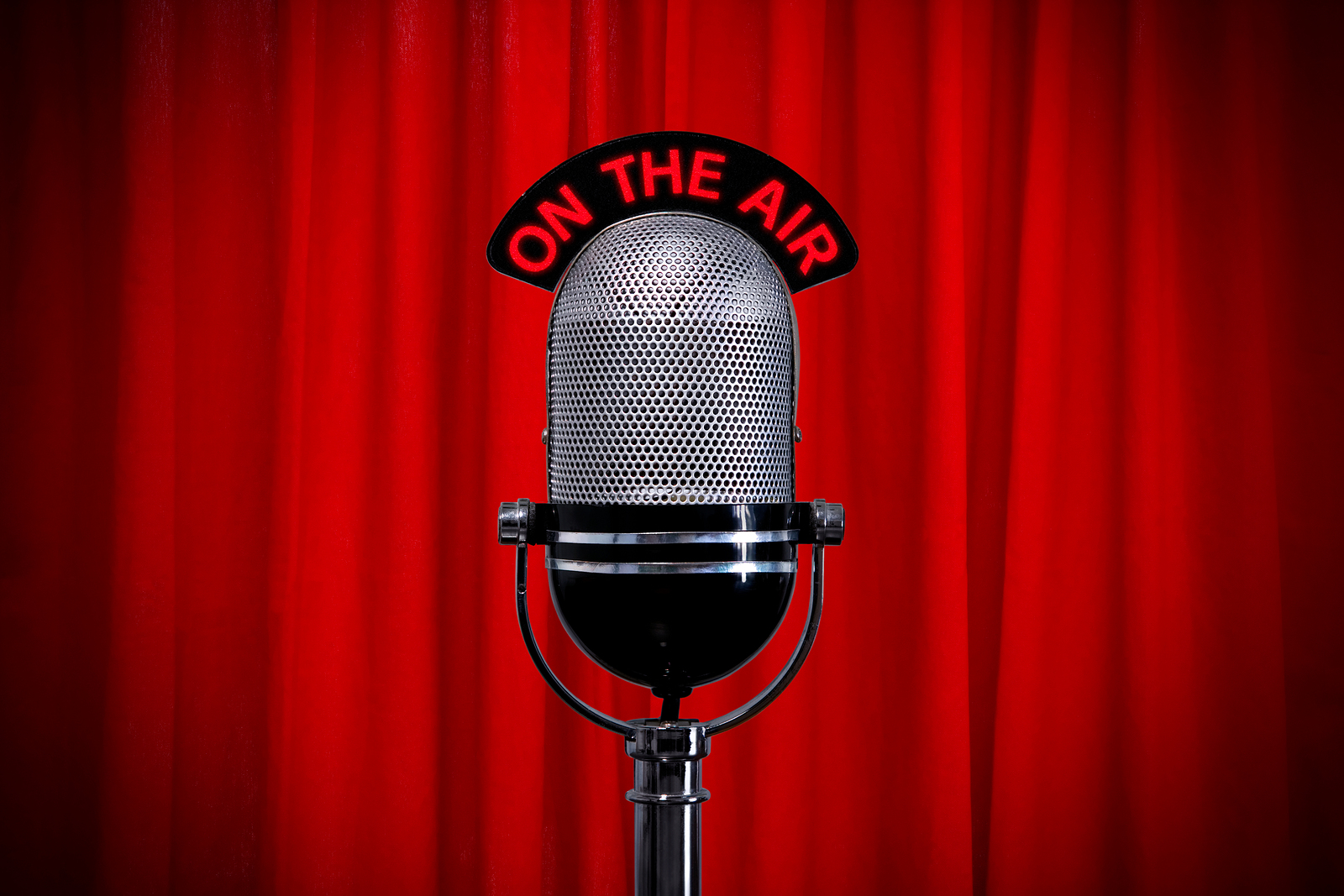 Microphone on stage with spotlight on red curtain